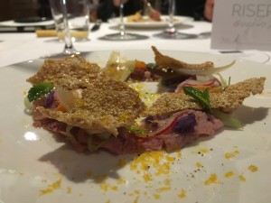 il Prosciutto di agnello al forno con tuorlo d’uovo affumicato, insalatina di stagione con patate viole, puntarelle, conserva di cipolla di Giarratana e cialdine di cuturro